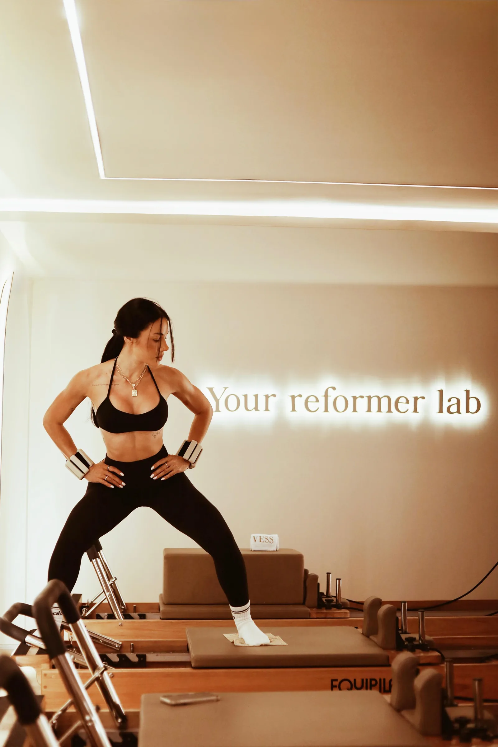 Instrutora ao lado do reformer sob o letreiro Your reformer lab